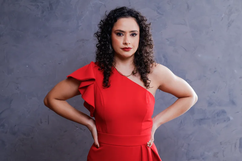 Retrato de uma mulher com vestido vermelho com as mãos na cintura.