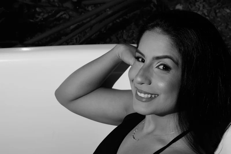 Retrato do rosto uma mulher em uma banheira, sorrindo para a câmera.